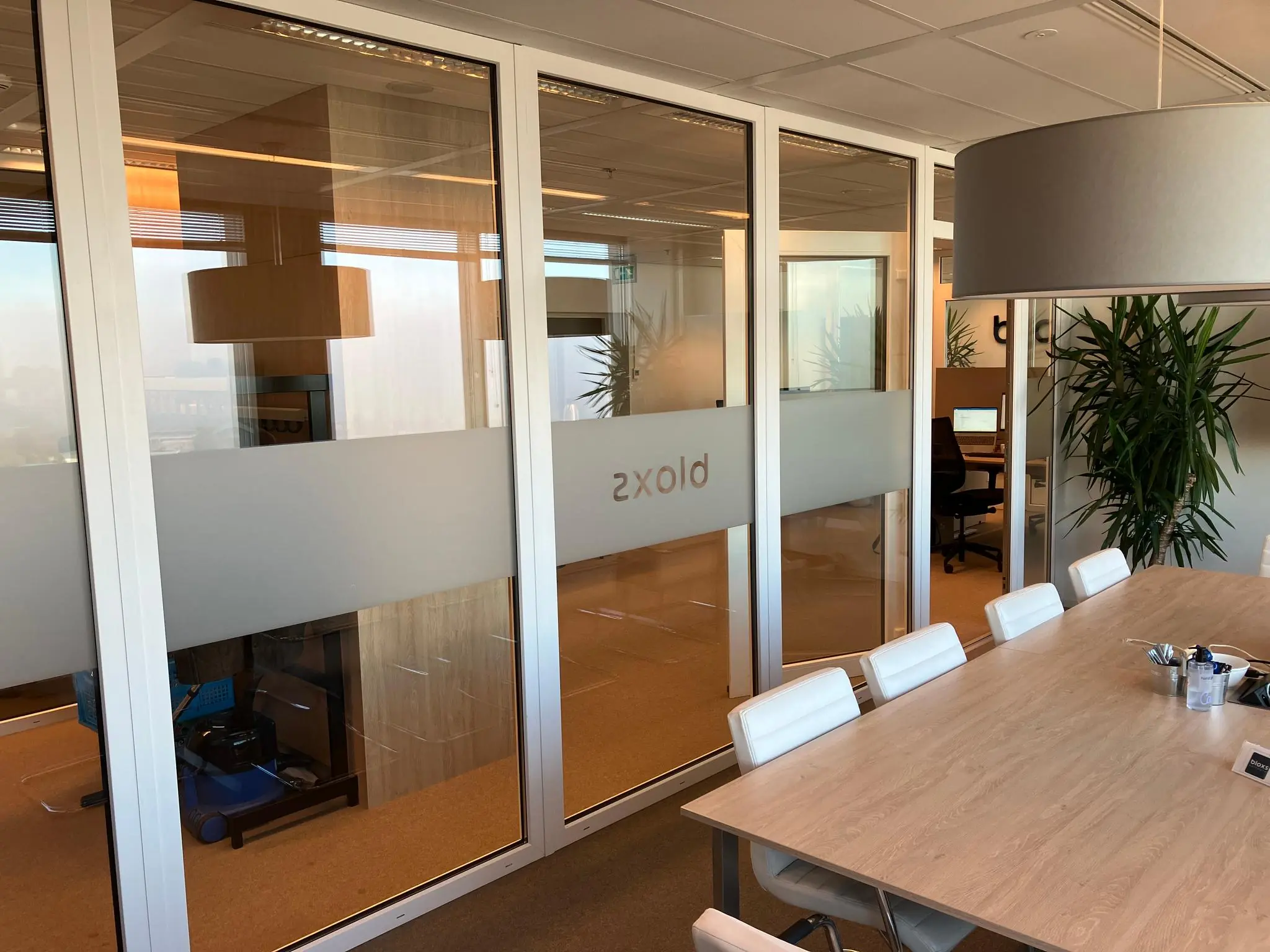 Vergaderruimte met houten tafel, witte stoelen en glazen wanden op een kantoor aan de Vliegend Hertlaan.